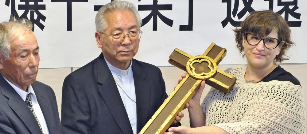 Tanya Maus gibt Erzbischof Joseph Mitsuaki Takami das 1945 aus den Trümmern der Kathedrale von Nagasaki geborgene Kreuz zurück.