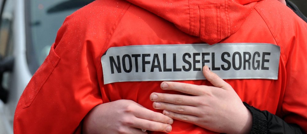Ein Notfallseelsorger umarmt tröstend eine Frau nach einem verheerenden Amoklauf.