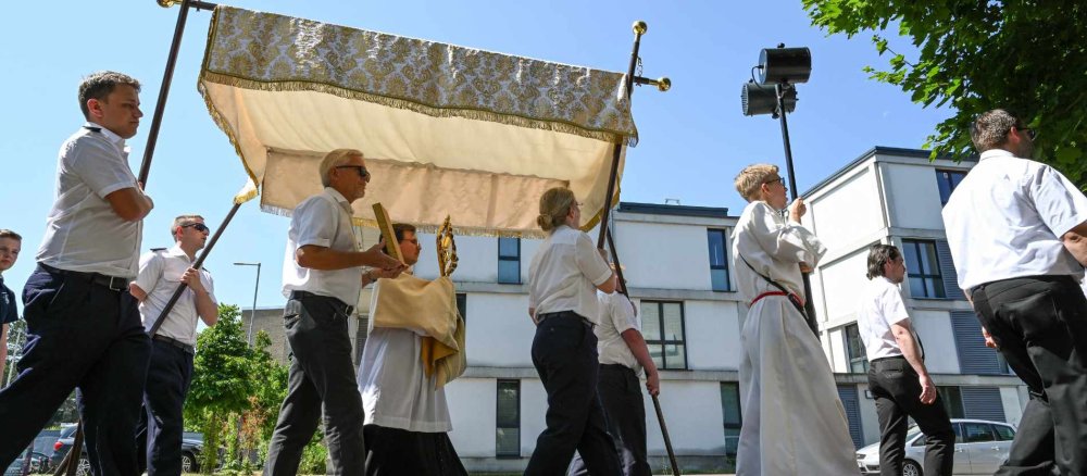 Ein Priester trägt unter einem Baldachin die Monstranz bei einer Fronleichnams-Prozession
