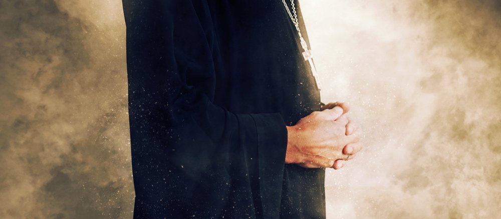 Ein Priester steht vor hellen Flammen