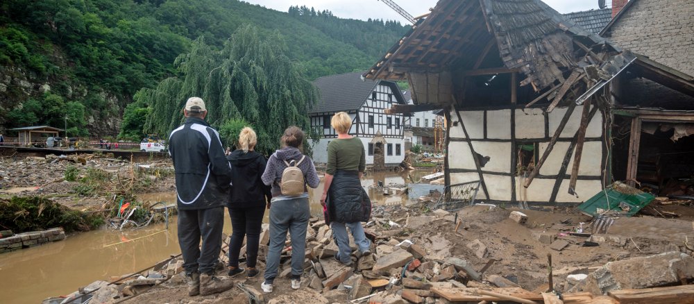 Menschen stehen neben einem zerstörten Haus in Ahrweiler