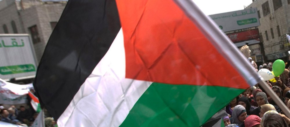 Frauen halten eine palästinensische Flagge in die Luft.