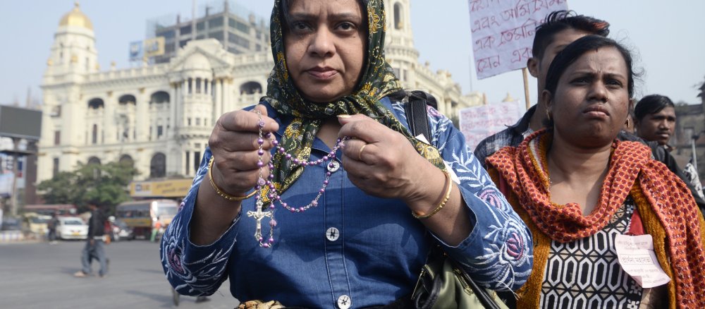 Eine indische Christin hält einen Rosenkranz in der Hand.