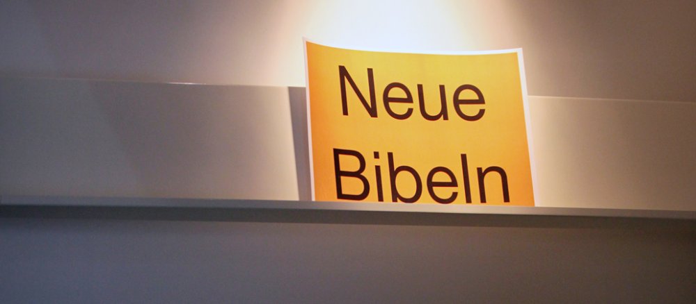 Ein Schild "Neue Bibeln" steht in einem leeren Bücherregal