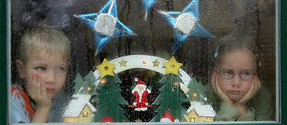 Kinder gucken in der Weihnachtszeit traurig aus dem Fenster.