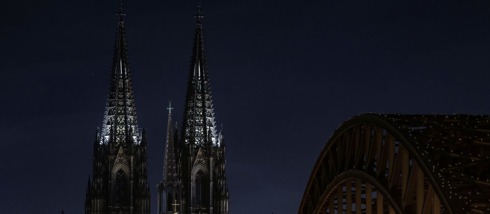 Die Spitzen der Türme des Kölner Doms leuchten am Morgen von innen.