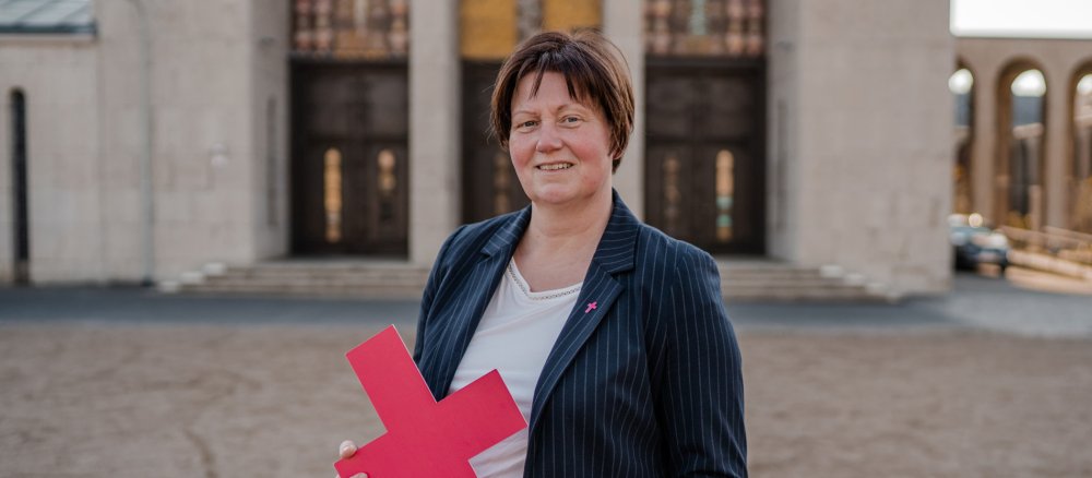 Porträt von Susanne Winnekens-Udovic mit einem Purpurkreuz in der Hand