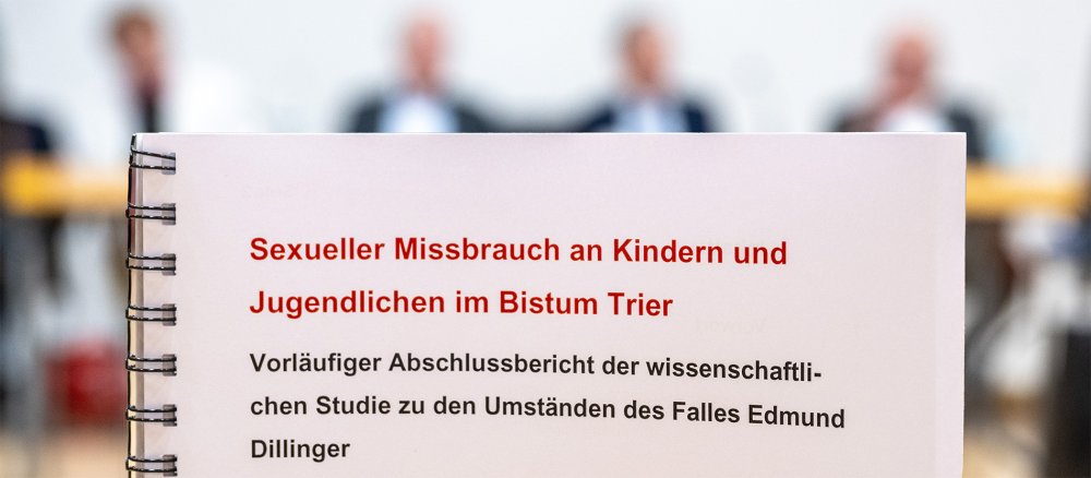 Titelseite des vorläufigen Abschlussberichts zum Fall Dillinger vor dem Podium der Pressekonferenz