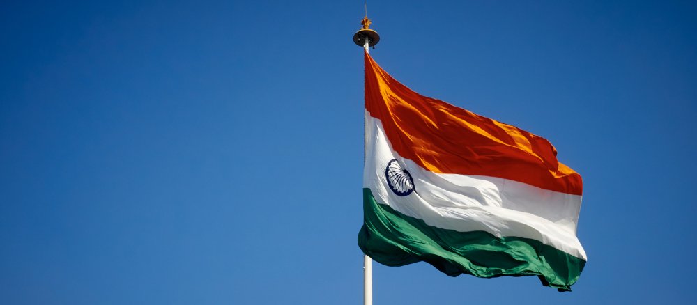 Die indische Flagge weht an einem Fahnenmast vor blauem Himmel.