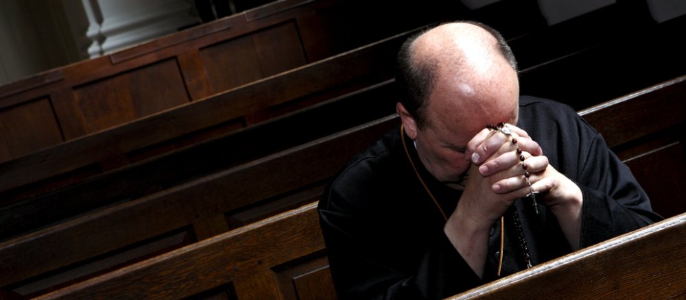 Ein Priester betet in einer Kirche.