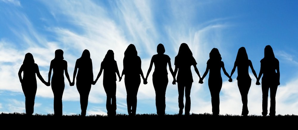 Zehn junge Frauen halten sich an der Hand.