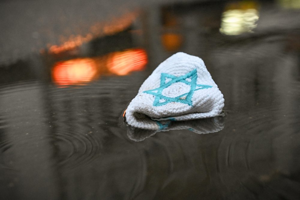 Eine Kippa mit einem Davidstern liegt auf der Straße in einer Pfütze