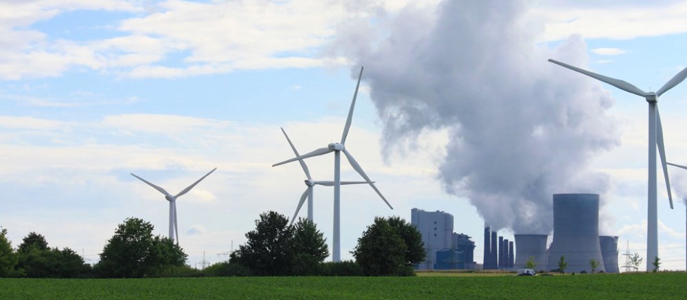 Eine grüne Wiese mit Windrädern und einem Kraftwerk