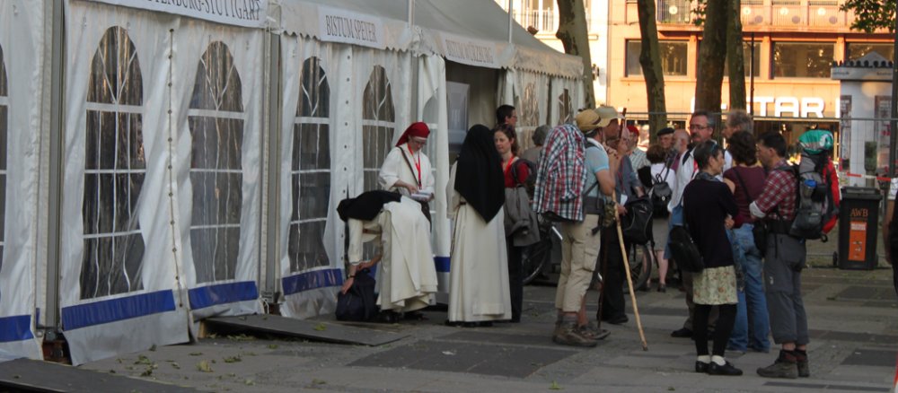 Eine Gruppe Pilger steht vor einem weißen Zelt in Köln am Neumarkt.