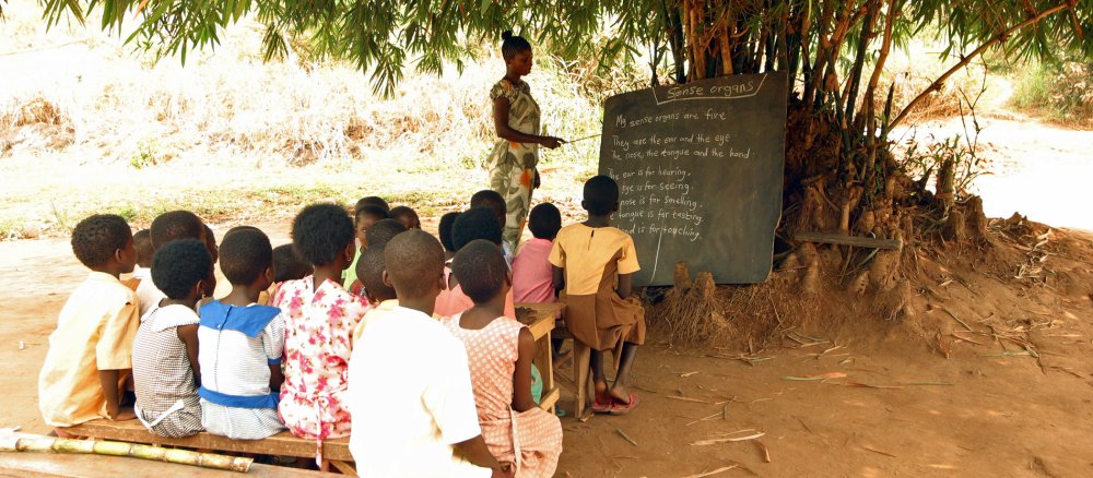 Unter einem Baum unterrichtet eine Lehrerin Schüler in Ghana
