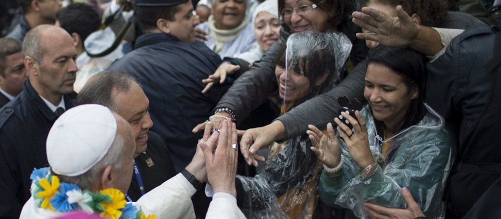 Der Papst (links unten) mit Blumenkette in den Brasilien-Farben um den Hals hält die Hände von zwei begeisterten brasilianischen Frauen (rechts oben). Eine dritte Frau macht ein Foto.