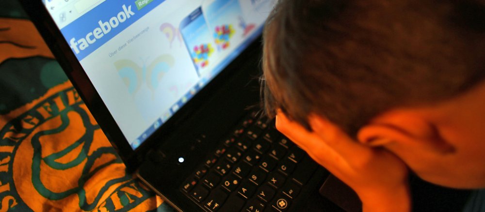 Symbolbild: Ein Junge sitzt vor der Facebook-Anmeldung