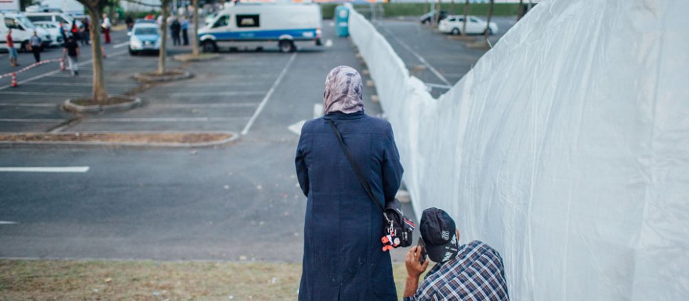 Ein Flüchtlingspaar schaut vor dem ehemaligen Praktiker-Baumarkt in Heidenau auf den Parkplatz.