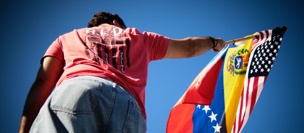 Ein Mann hält eine venezoelanische und eine US-Flagge