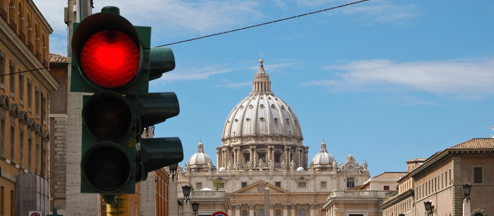 Red traffic light in front of the dome of St Peter's Basilica