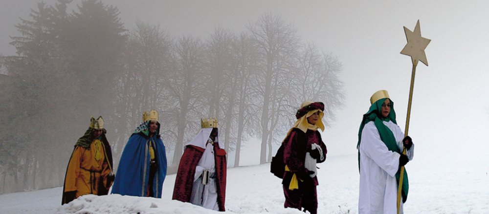 Die Sternsinger wandern durch den Schnee zum nächsten Dorf.