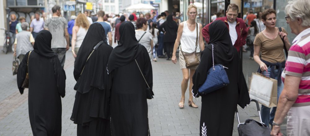 Muslimische Frauen in Nikab gehen durch eine Fußgängerzone.