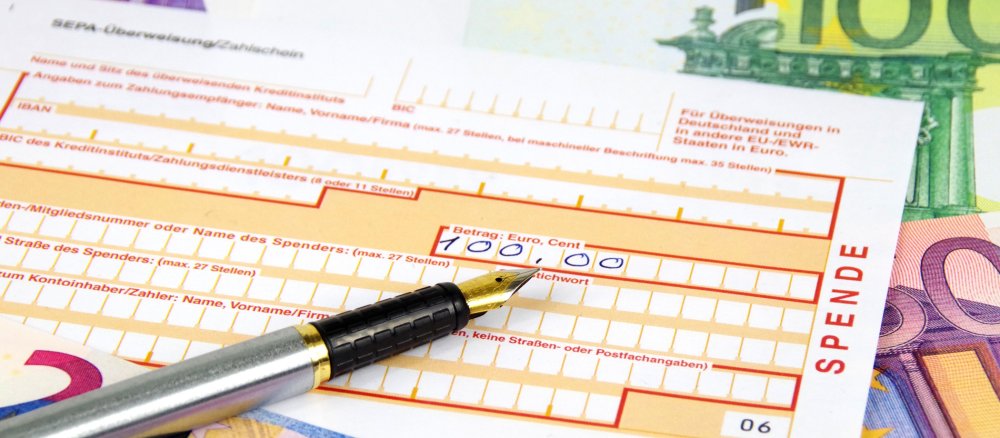 Spenden-Überweisungsformular mit Stift und Euro-Banknoten