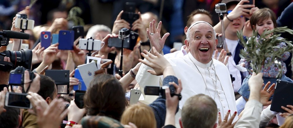 Papst Franziskus feiert den Gottesdienst am Palmsonntag auf dem Petersplatz am 20. März 2016 in Rom. Bild: Papst Franziskus verläßt den Petersplatz. Er winkt und lacht den Zuschauern zu, die ihn mit Handys fotografieren.