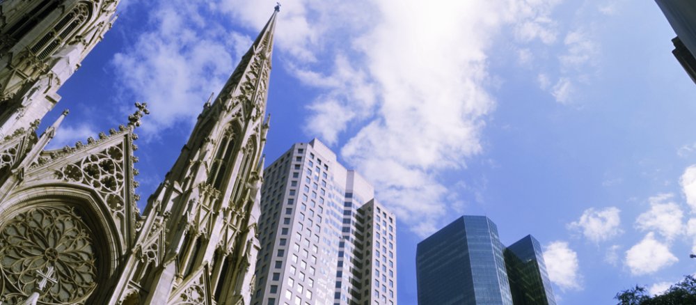 Das Bild zeigt sich Kirche und daneben einige Hochhäuser.