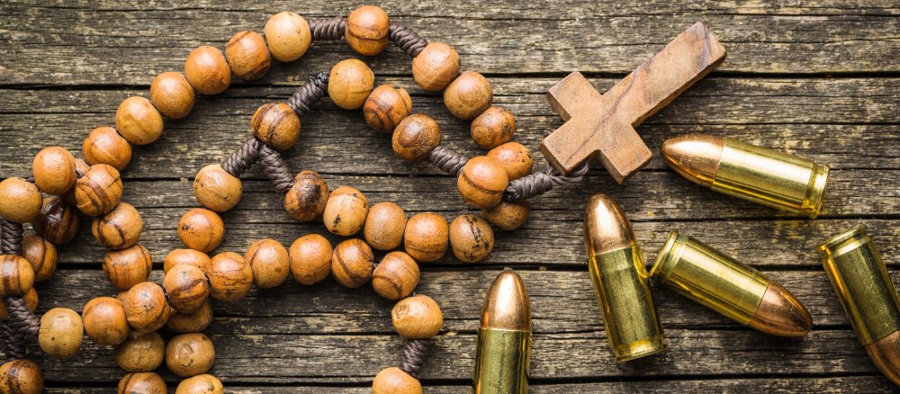 A wooden rosary lies next to scattered pistol cartridges.