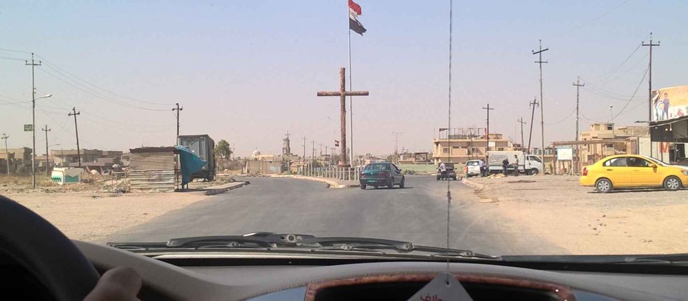 An der Ortseinfahrt von Karakosch steht ein großes Holzkreuz.