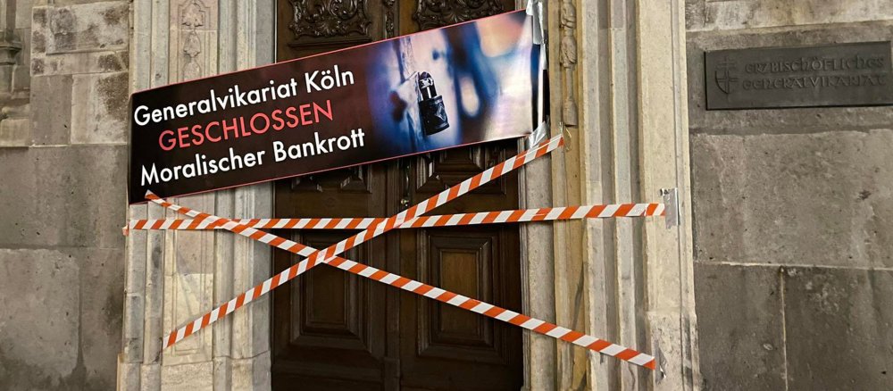 Das Hauptportal des Kölner Generalvikars symbolisch mit Flatterband und einem Protestplakat abgesperrt.