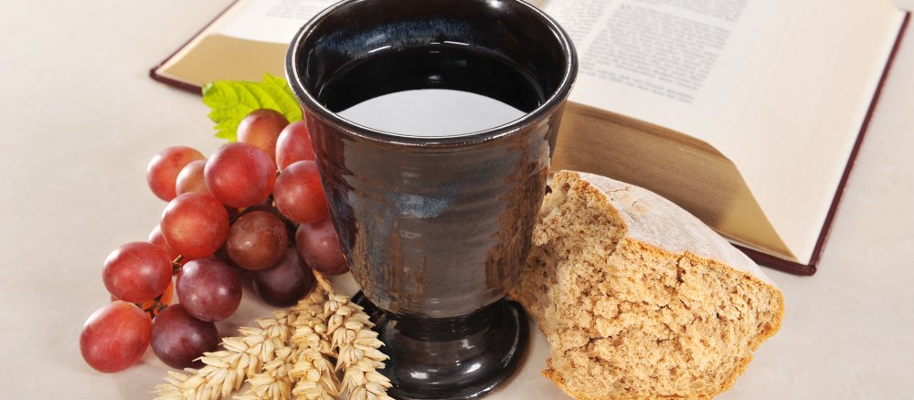 Brot und Wein mit einer aufgeschlagenen Bibel im Hintergrund