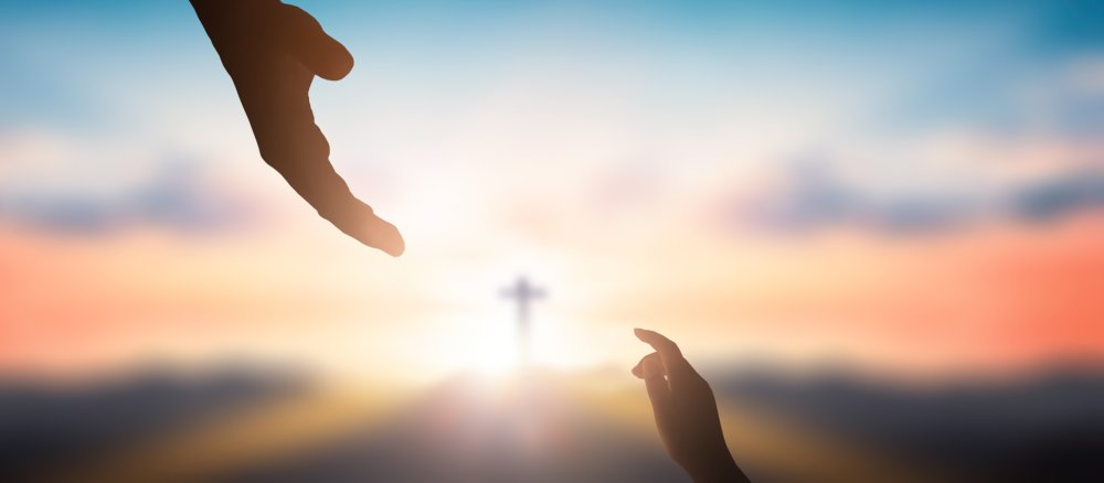 Zwei ausgestreckte Hände, im Hintergrund ein Kreuz