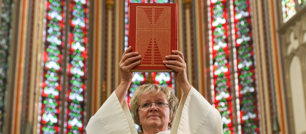 Eine Frau hält im Gottesdienst ein Lektionar hoch