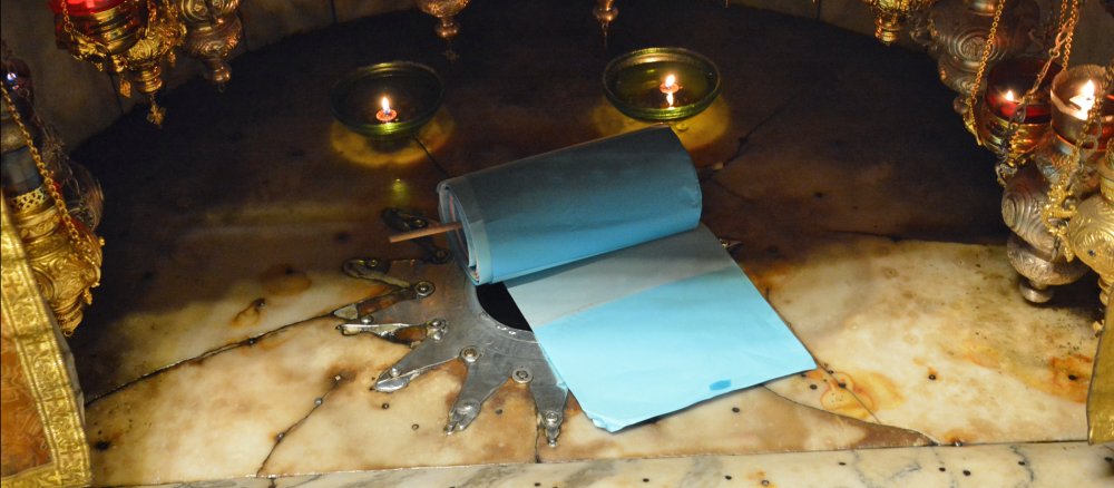 A blue paper scroll lies on the stone floor of a chapel with a silver star embedded in it.