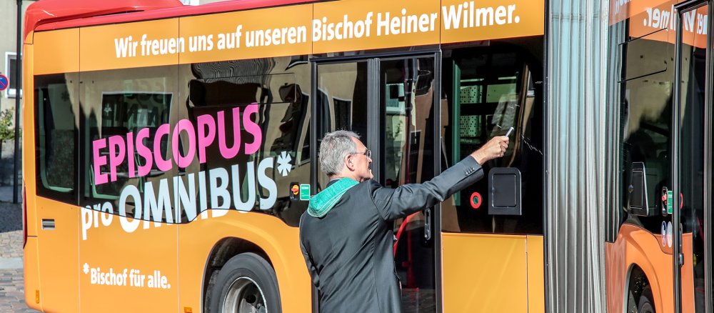 Bus mit Aufschrift "Episcopus pro Omnibus" wird gesegnet