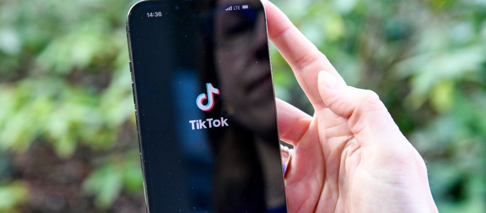 Eine Frau hält ein Handy, auf dem die App TikTok geöffnet wird