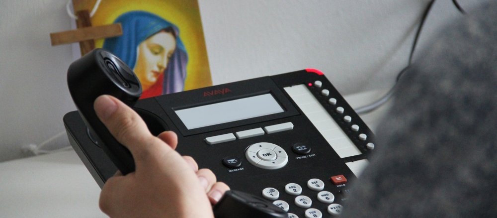 Ein Mann sitzt vor einem Telefon und will telefonieren.