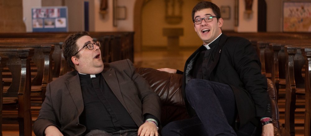 Die Priester Christoph Hendrix und Ralf Meyer sitzen auf einem Sofa in einer Kirche