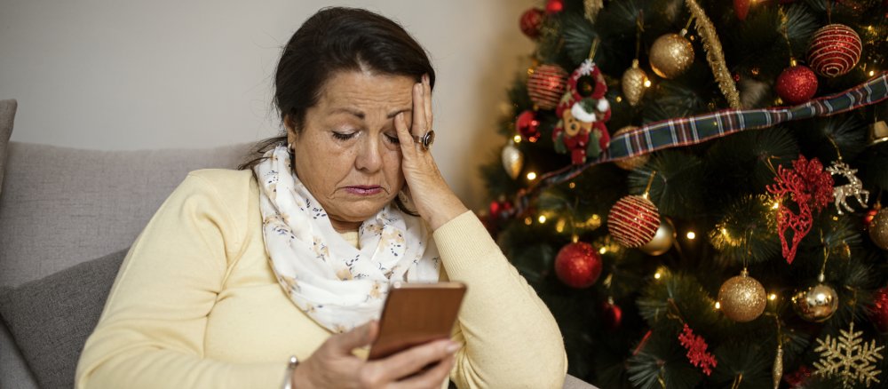 Eine ältere Frau sitzt neben dem Weihnachtsbaum