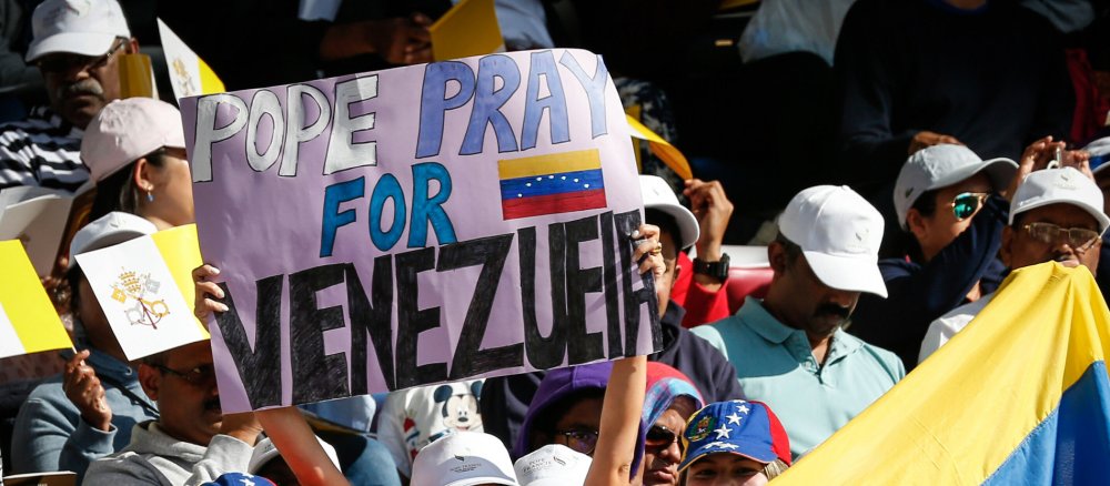 A woman holds up a sign that reads "Pope Pray for Venezuela"