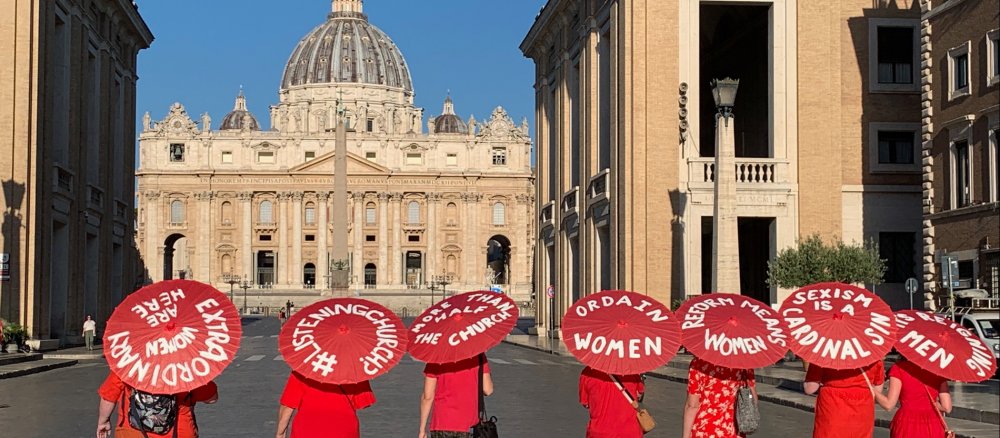 Sieben Frauen demonstrieren mit roten Schirmen vor dem Vatikan für Frauenrechte in der Kirche