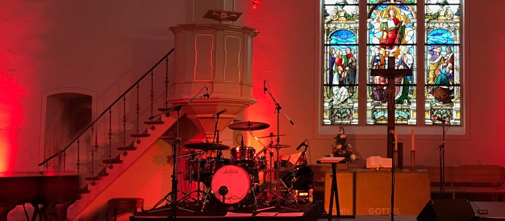 Ein Schlagzeug steht in einer rot erleuchteten Kirche