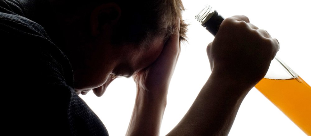 Ein frustriert vor sich hin schauender Mann versucht seine Probleme mit Alkohol zu lösen