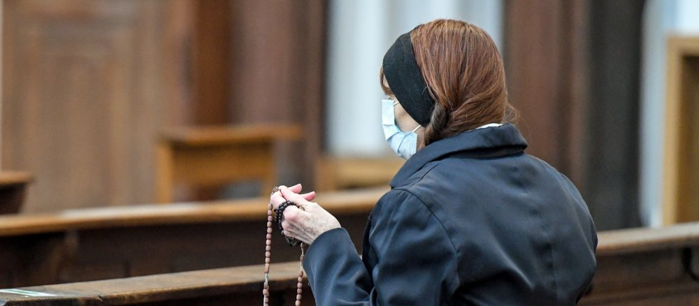 Eine Frau mit Mundschutz betet
