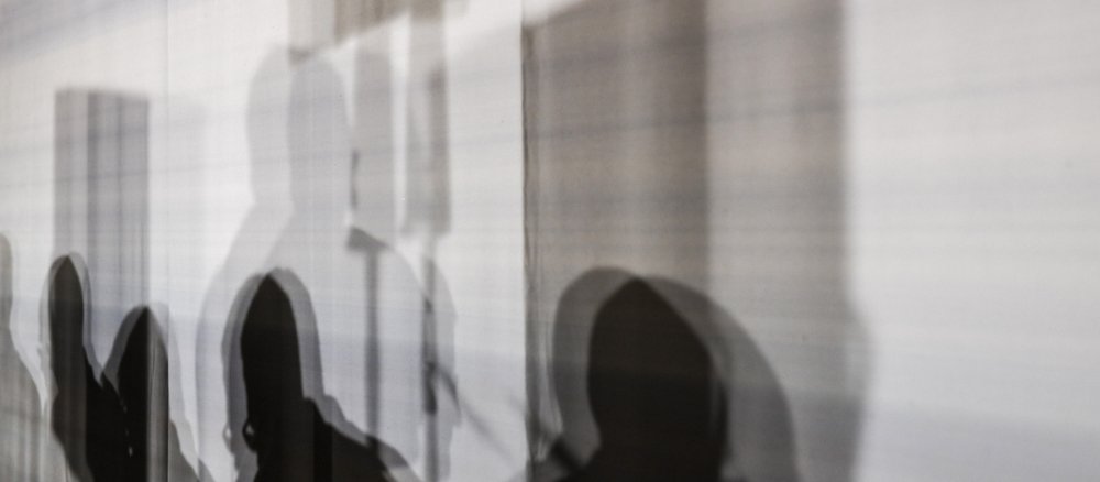 Menschen im Gespräch, darüber ein Kreuz