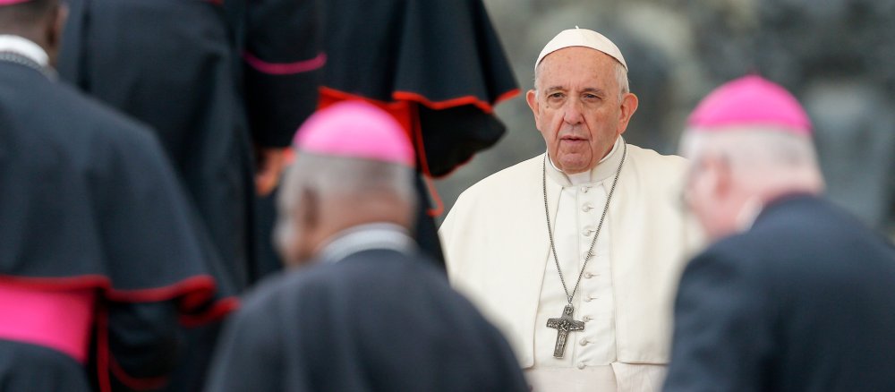 Pope Francis stands between bishops during the general audience at the Vatican.