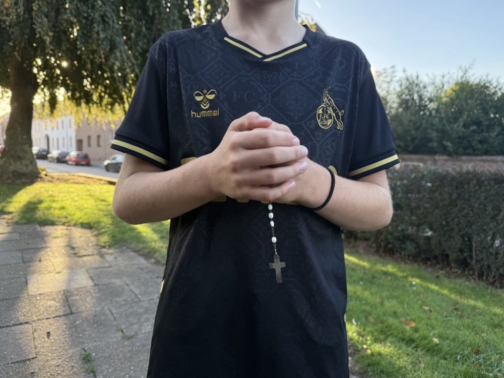 Ein Kind hält einen Rosenkranz in der Hand.