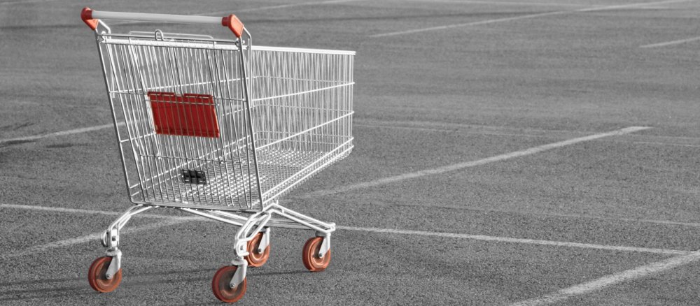 Ein leerer Einkaufswagen steht auf einem verlassenen Parkplatz